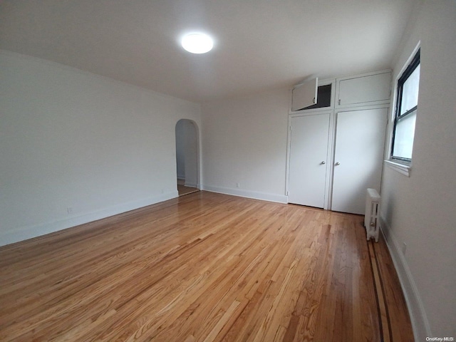 unfurnished bedroom with radiator heating unit and light wood-type flooring