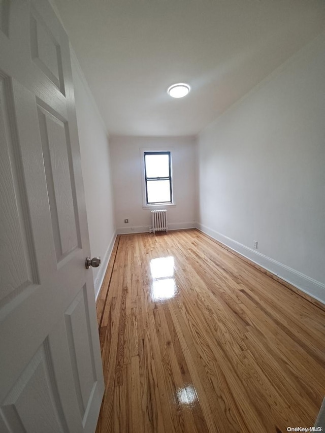 spare room featuring radiator heating unit and light wood-type flooring