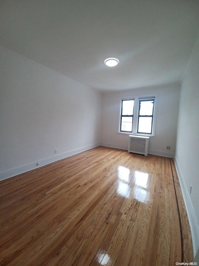 unfurnished room featuring radiator heating unit and light wood-type flooring