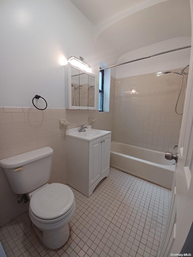 full bathroom featuring vanity, tile patterned floors, tiled shower / bath combo, toilet, and tile walls