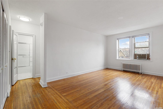 unfurnished room featuring cooling unit, wood-type flooring, radiator heating unit, and a textured ceiling