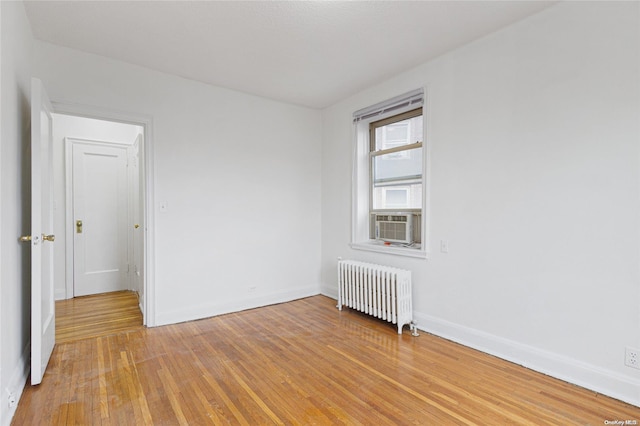 unfurnished room with radiator heating unit, cooling unit, and hardwood / wood-style floors