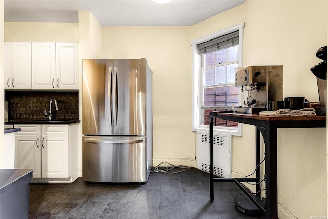 kitchen featuring decorative backsplash, stainless steel fridge, white cabinetry, and radiator