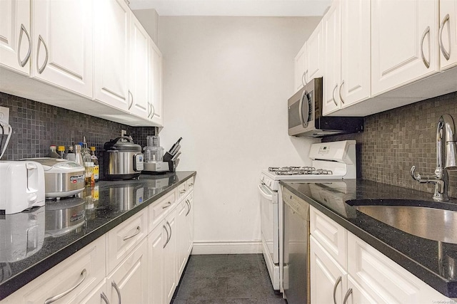 kitchen with decorative backsplash, dark tile patterned flooring, white cabinetry, and gas range gas stove