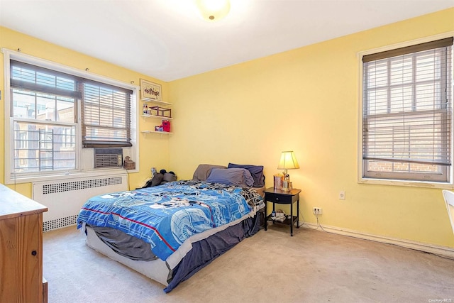 carpeted bedroom with cooling unit, radiator, and multiple windows