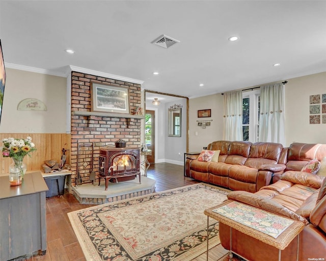 living room featuring a wood stove, crown molding, and wood-type flooring