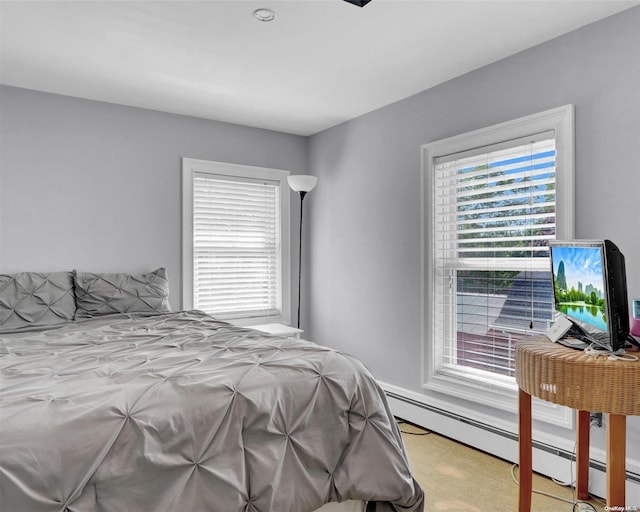 carpeted bedroom featuring baseboard heating and multiple windows