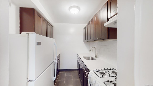 kitchen featuring sink, white appliances, dark tile patterned floors, backsplash, and dark brown cabinetry