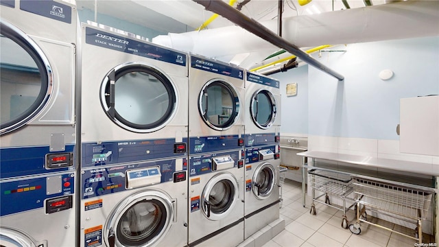 laundry area featuring stacked washing maching and dryer, light tile patterned flooring, and washing machine and dryer