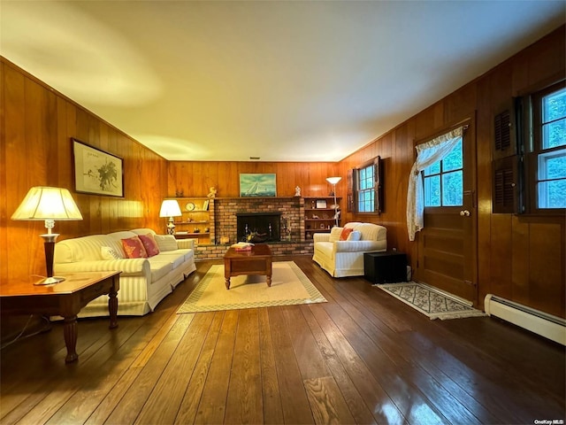 living room with baseboard heating, wood walls, dark hardwood / wood-style floors, and a brick fireplace