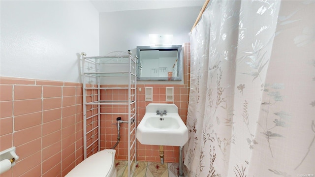 bathroom featuring toilet, tile walls, and sink