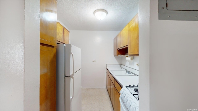 kitchen featuring a textured ceiling, white appliances, and sink