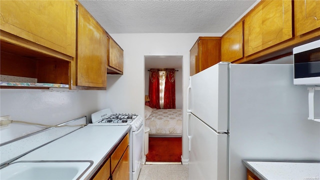 kitchen featuring a textured ceiling, white appliances, and sink