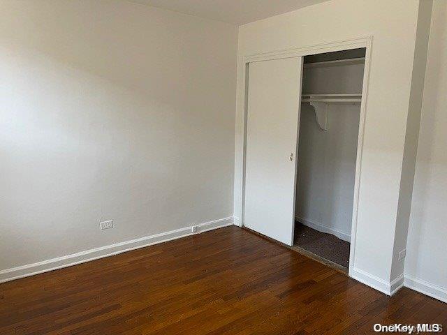 unfurnished bedroom featuring a closet and dark hardwood / wood-style floors