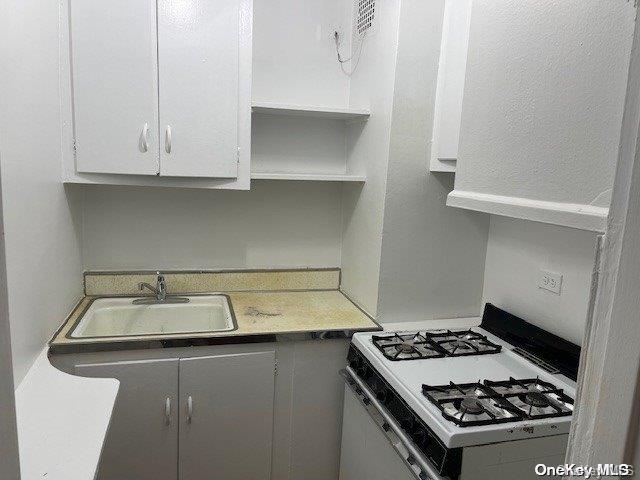 kitchen featuring white cabinetry, white gas range, and sink