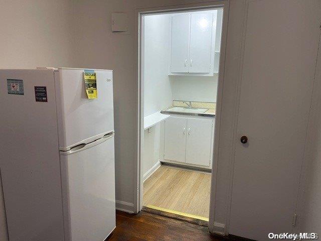 kitchen featuring white cabinets, sink, white fridge, and dark wood-type flooring