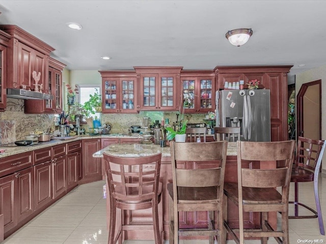 kitchen featuring backsplash, stainless steel fridge with ice dispenser, a breakfast bar, and light tile patterned flooring