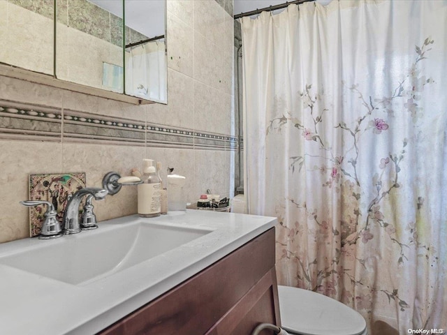 bathroom featuring vanity, toilet, walk in shower, and tile walls