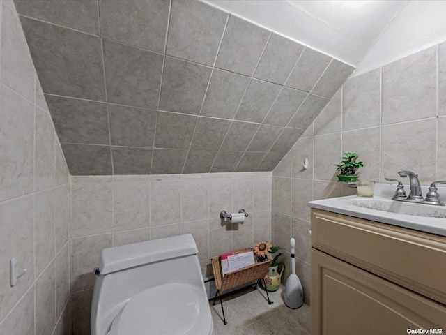 bathroom featuring vanity, toilet, lofted ceiling, and tile walls