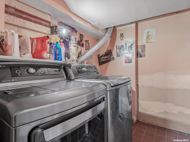 laundry room with washing machine and clothes dryer and dark tile patterned flooring