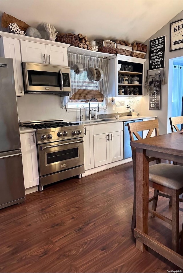 kitchen with dark hardwood / wood-style flooring, white cabinetry, appliances with stainless steel finishes, and vaulted ceiling