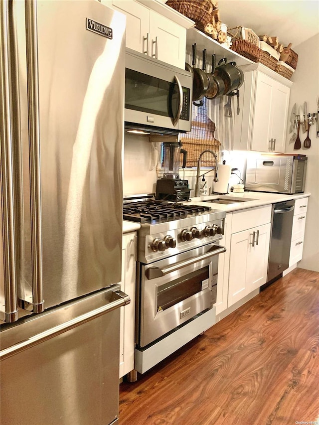 kitchen featuring dark hardwood / wood-style floors, high quality appliances, white cabinetry, and sink