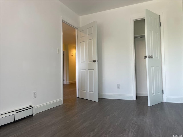 unfurnished bedroom featuring baseboard heating, a closet, and dark hardwood / wood-style flooring