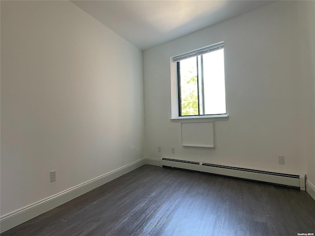 spare room featuring dark wood-type flooring and a baseboard heating unit