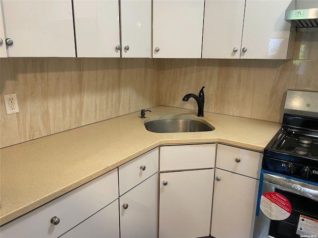 kitchen featuring stainless steel range, white cabinetry, sink, and ventilation hood