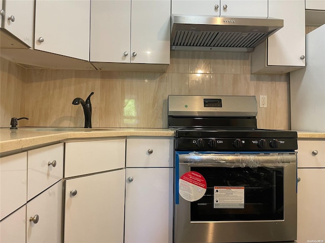 kitchen with white cabinetry, decorative backsplash, stainless steel range with gas cooktop, and extractor fan