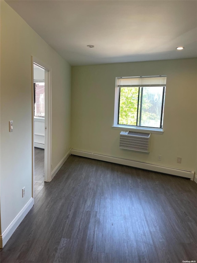 spare room with dark wood-type flooring, a wall unit AC, and a baseboard heating unit