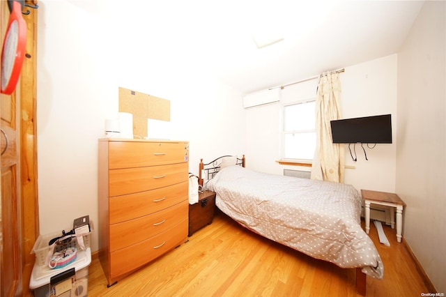 bedroom with hardwood / wood-style flooring and a wall mounted air conditioner