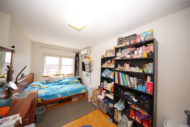 bedroom with a wall mounted air conditioner and light wood-type flooring