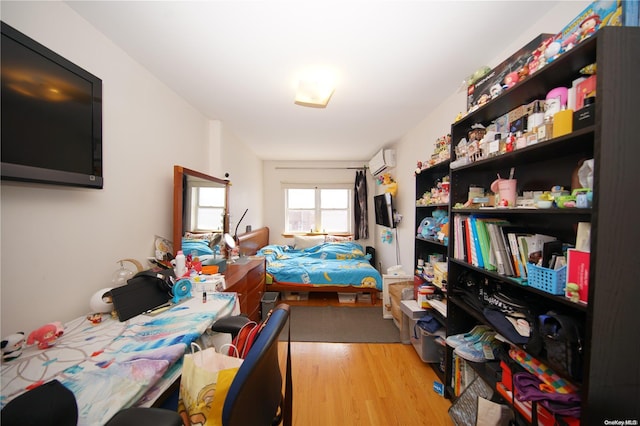 bedroom featuring a wall unit AC and light hardwood / wood-style floors