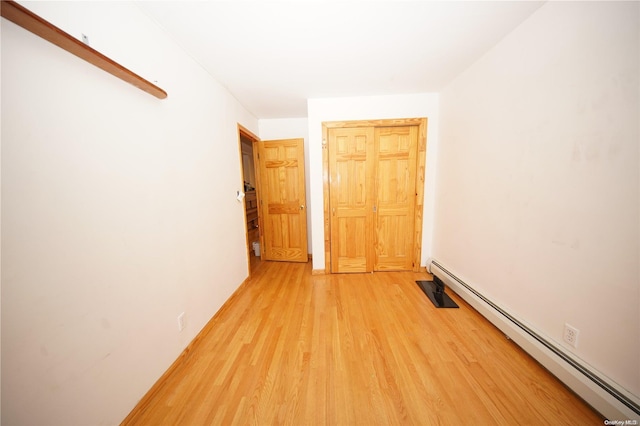 unfurnished room with hardwood / wood-style floors and baseboard heating