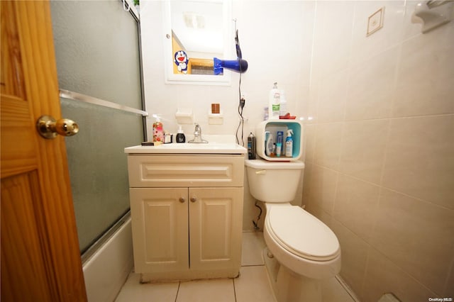 full bathroom featuring vanity, tile patterned floors, toilet, enclosed tub / shower combo, and tile walls