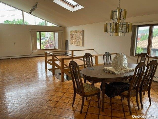 dining space with parquet flooring, vaulted ceiling with skylight, and an inviting chandelier