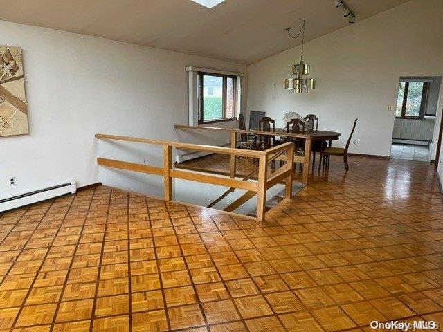 dining area with lofted ceiling, baseboard heating, parquet flooring, and an inviting chandelier