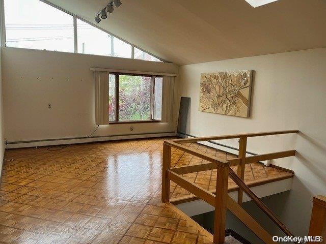 interior space with vaulted ceiling, a baseboard radiator, and light parquet flooring