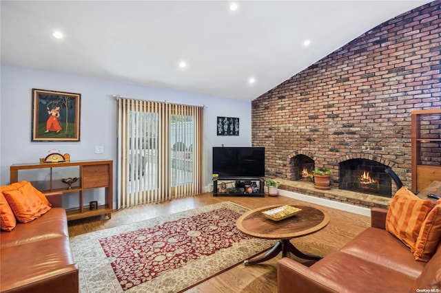 living room with hardwood / wood-style floors, a brick fireplace, and lofted ceiling