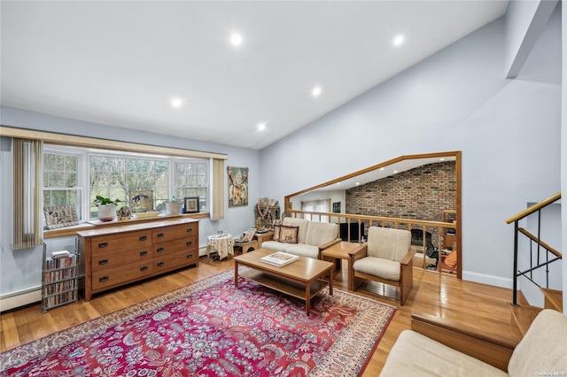 living room featuring high vaulted ceiling, a fireplace, light wood-type flooring, and baseboard heating