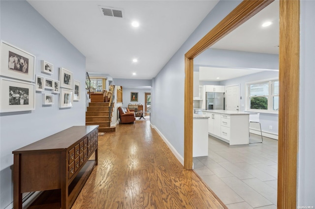 corridor with baseboard heating and light hardwood / wood-style flooring