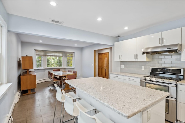 kitchen featuring range with two ovens, a kitchen bar, a kitchen island, white cabinetry, and a baseboard radiator