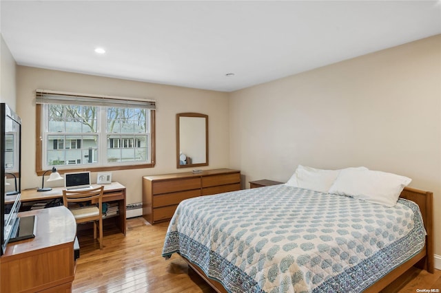 bedroom featuring light hardwood / wood-style floors and a baseboard heating unit