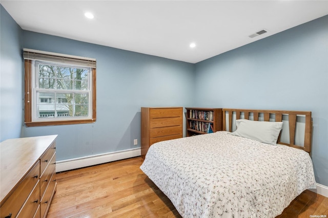 bedroom featuring a baseboard heating unit and light wood-type flooring