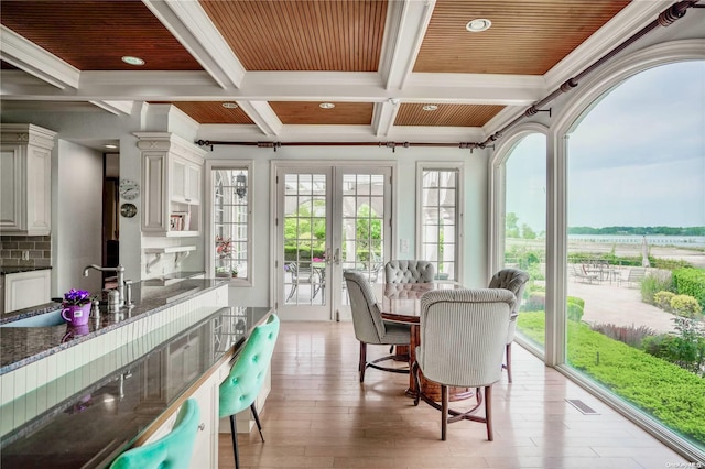 sunroom featuring coffered ceiling, a healthy amount of sunlight, sink, and french doors