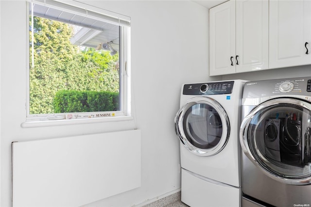 laundry area with washing machine and dryer, a wealth of natural light, and cabinets