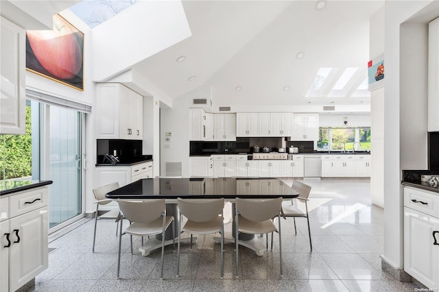 kitchen with white cabinets, decorative backsplash, high vaulted ceiling, and a healthy amount of sunlight