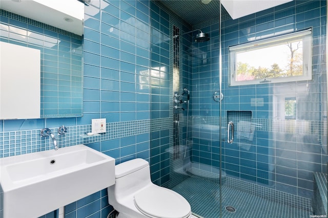 bathroom featuring sink, a shower with door, tile walls, and toilet