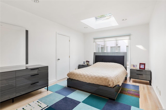 bedroom featuring light wood-type flooring and a skylight